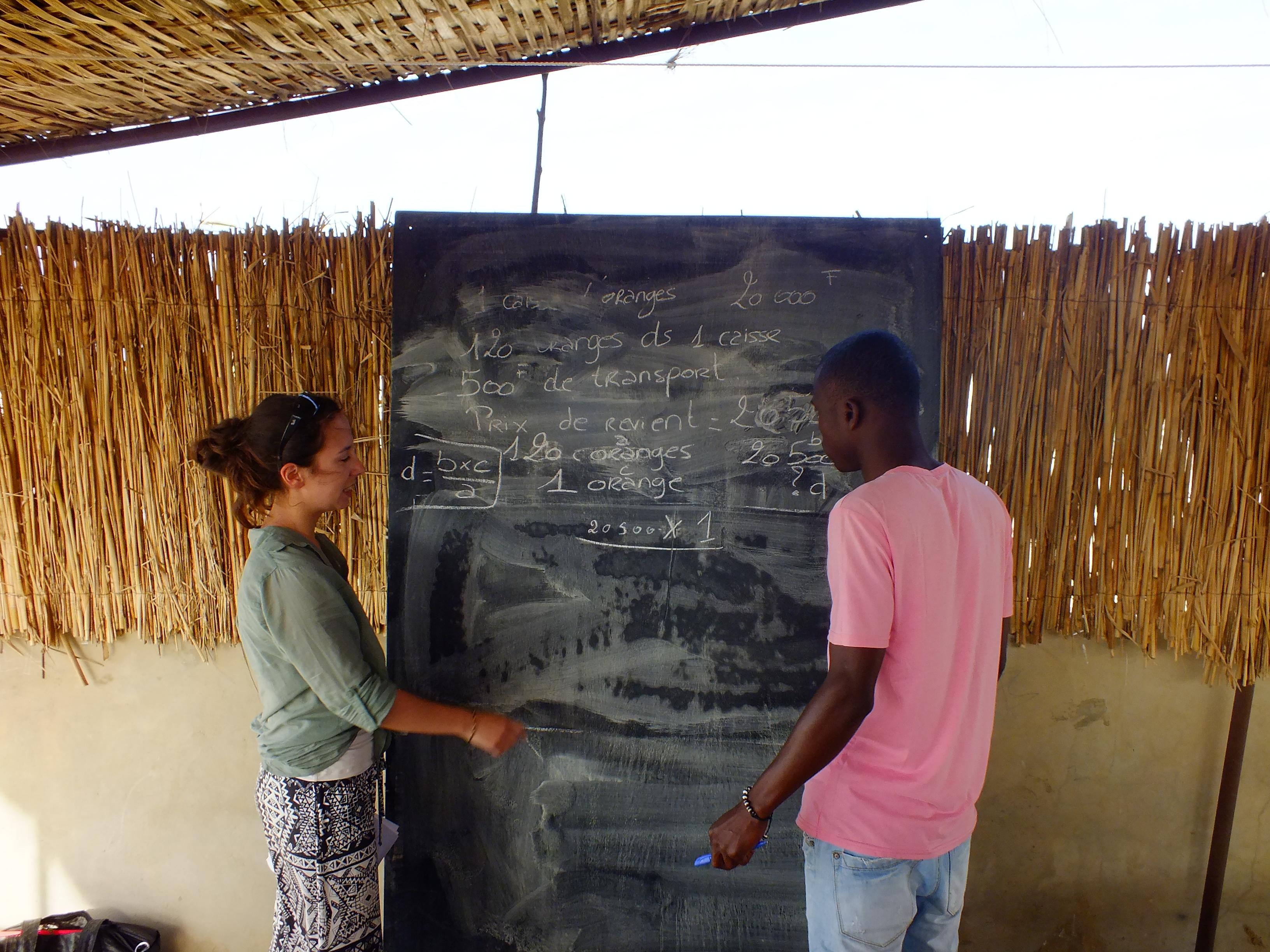 A Projects Abroad volunteer speaks to a local at her placement in Senegal. A Teaching volunteer in Senegal helps a local boy during a lesson.